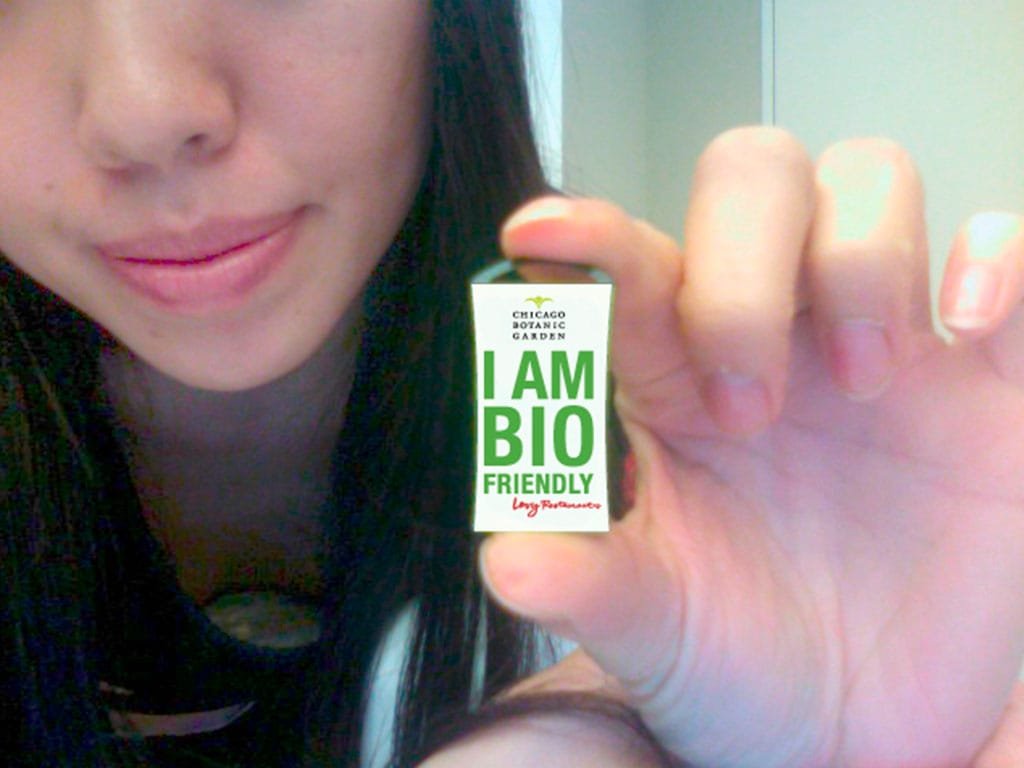 Hand holding a small green USB drive printed I Am Bio Friendly