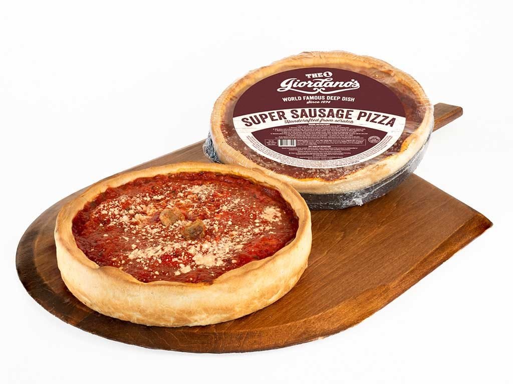 Baked Giordano's deep dish pizza beside a packaged one on a wooden board
