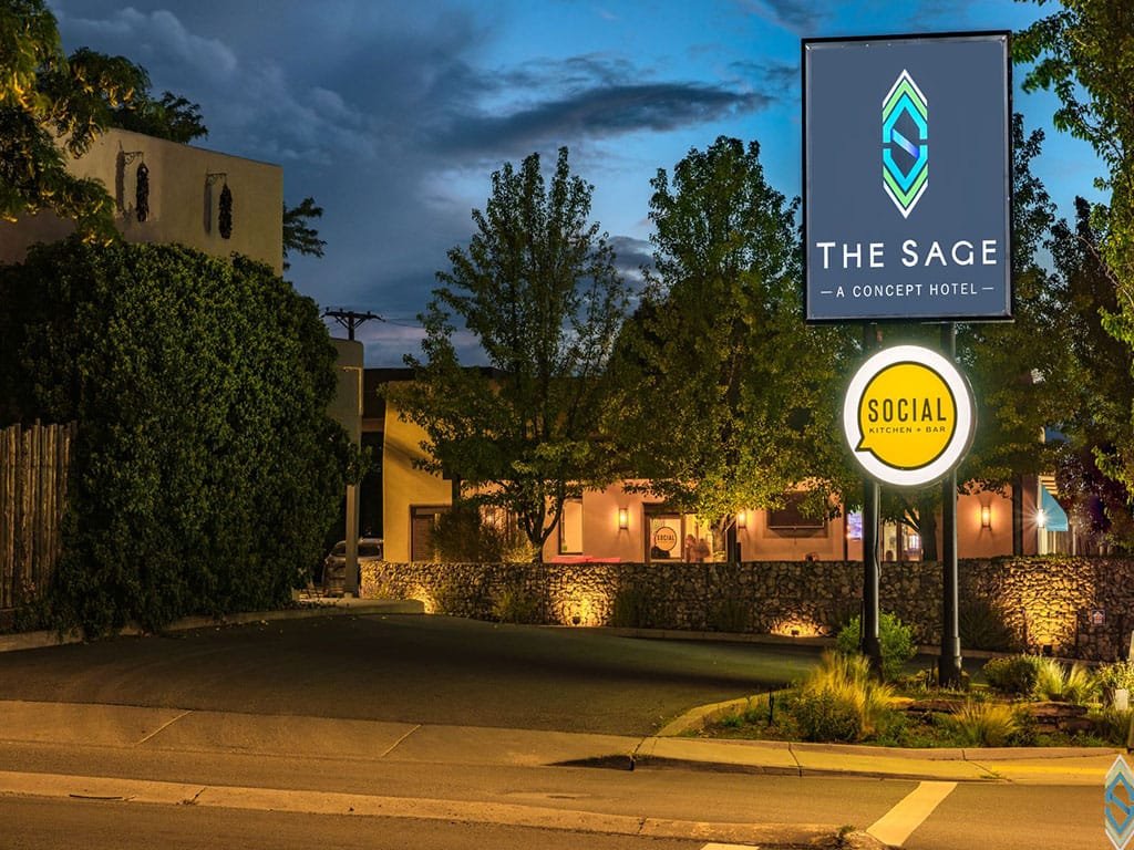 Illuminated Social sign below The Sage hotel sign at dusk